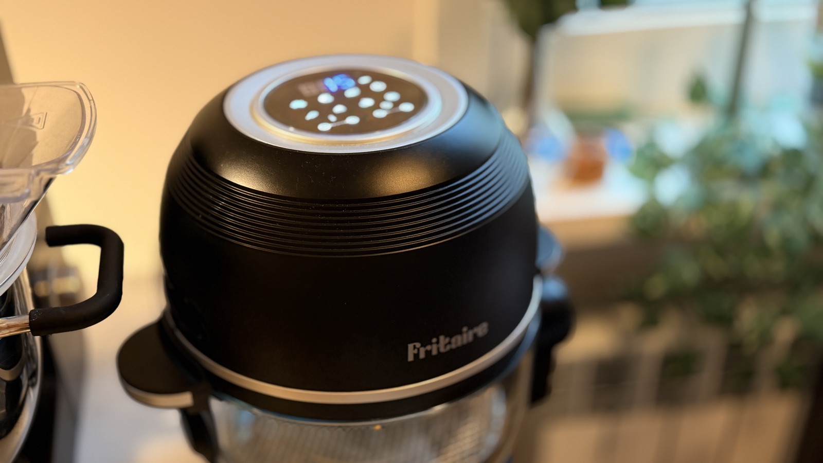 Fritaire airfryer i svart på köksbänken med upplyst kontrollpanel på locket