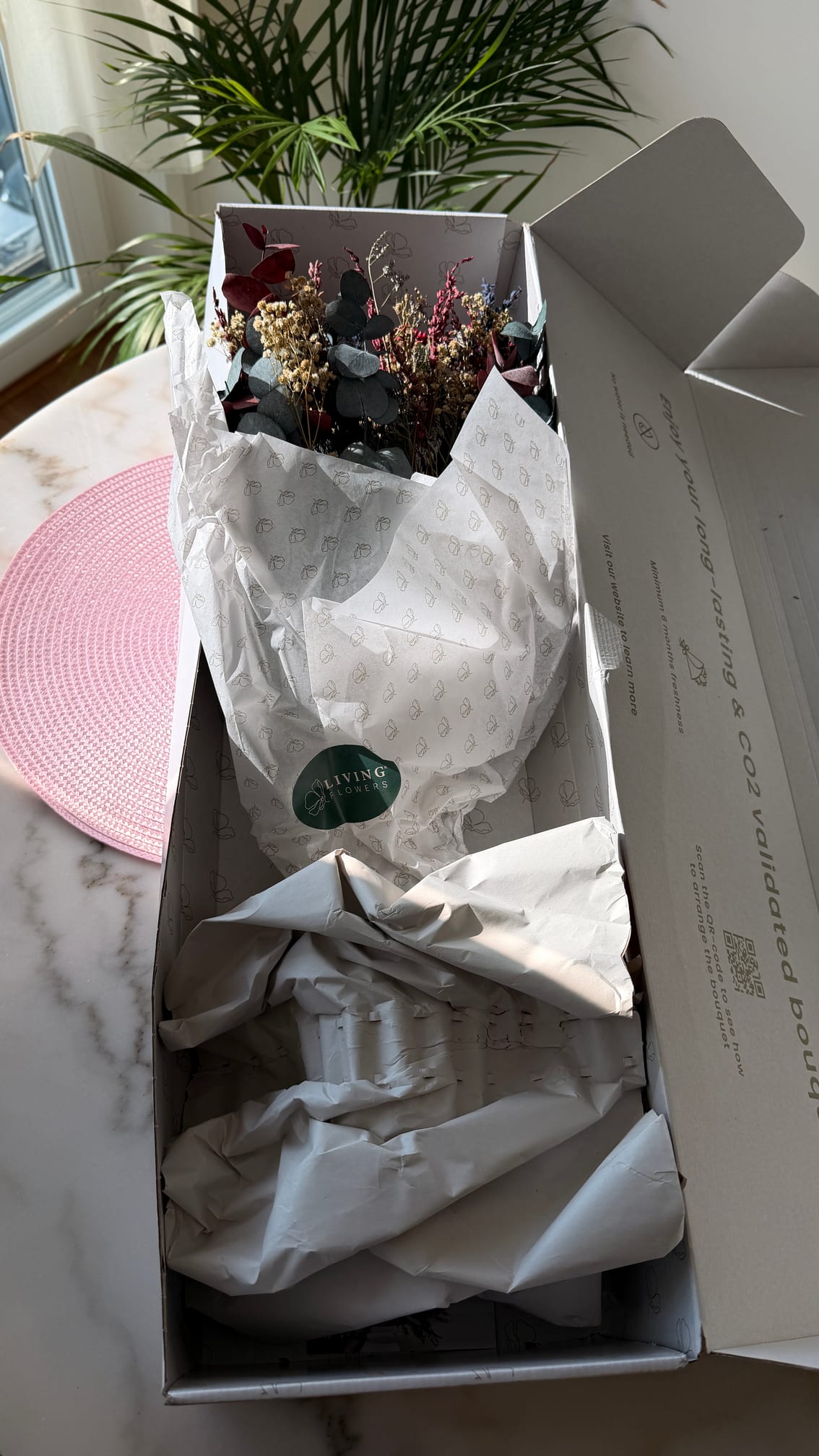 Living Flowers leveranslåda öppnad med buketten i silkespapper